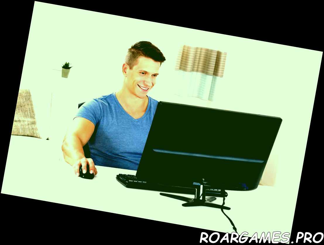 Joven hombre feliz usando una computadora de escritorio en la sala de estar